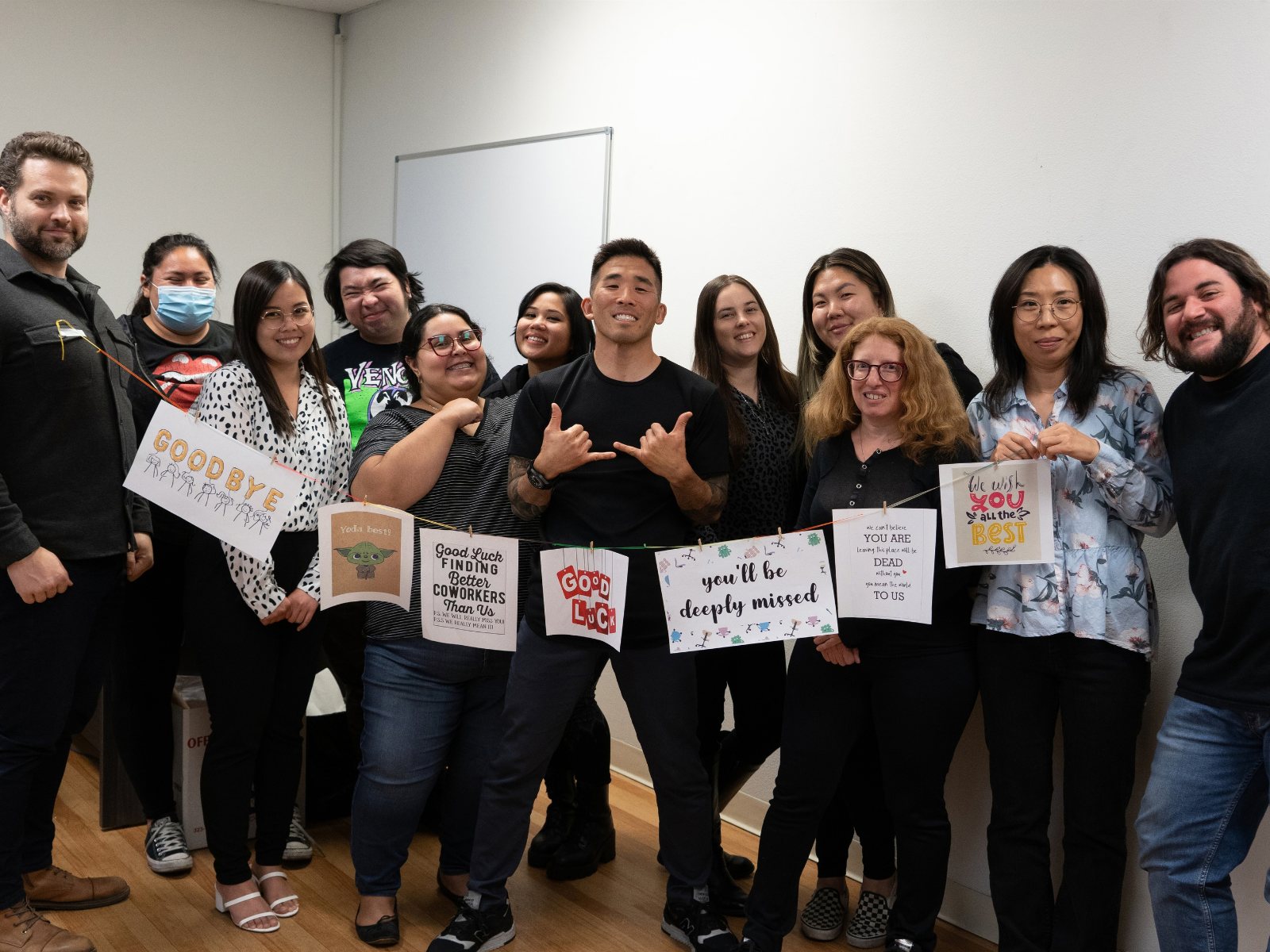 Tim Hirata with the CAG team holding a handmade goodbye banner
