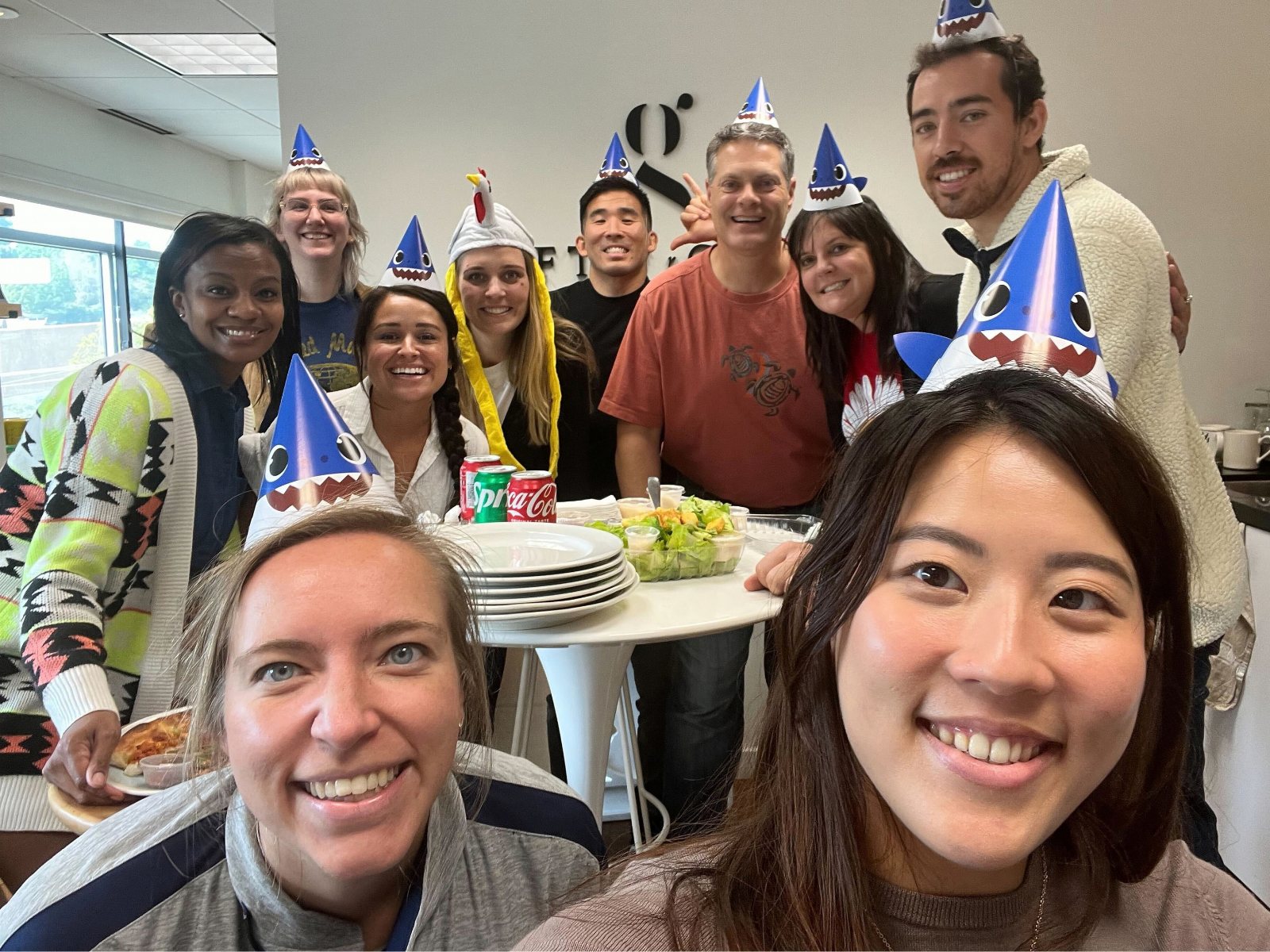 Tim Hirata with the Gifts for Good team in party hats around a table in the office